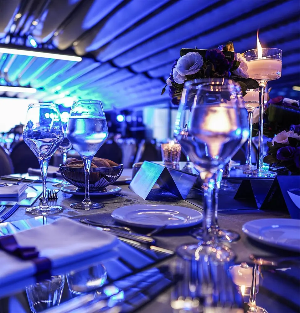 Cette image montre une partie d'une table d'événement décorée avec un orchestre flou en arrière-plan.